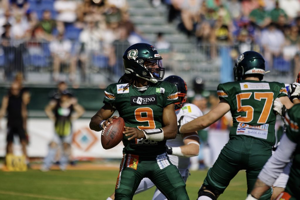 Hurricanes Quarterback PJ Settles im grünen Trikot mit der Nummer 9 macht sich zum Wurf bereit.
