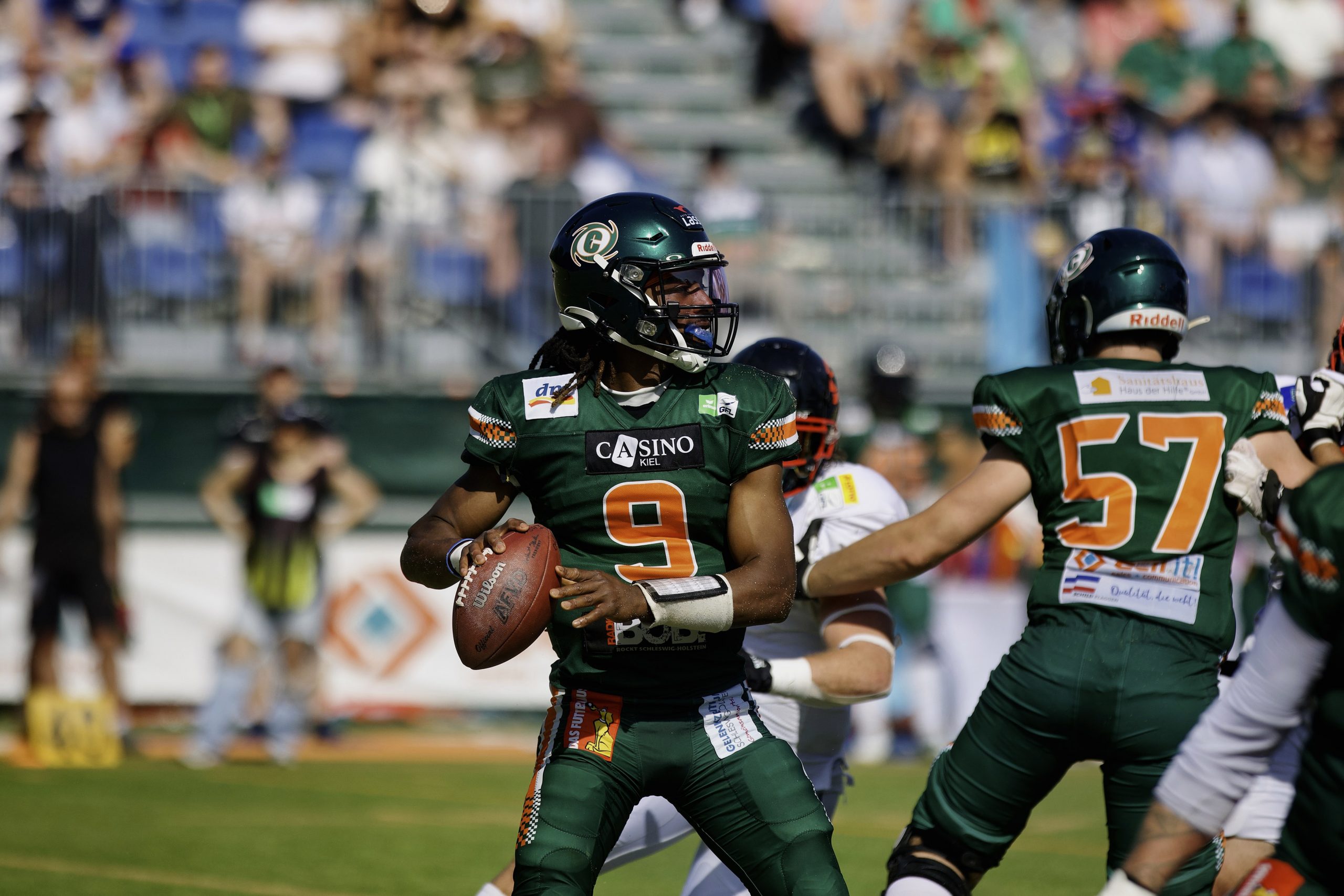Hurricanes Quarterback PJ Settles im grünen Trikot mit der Nummer 9 macht sich zum Wurf bereit.